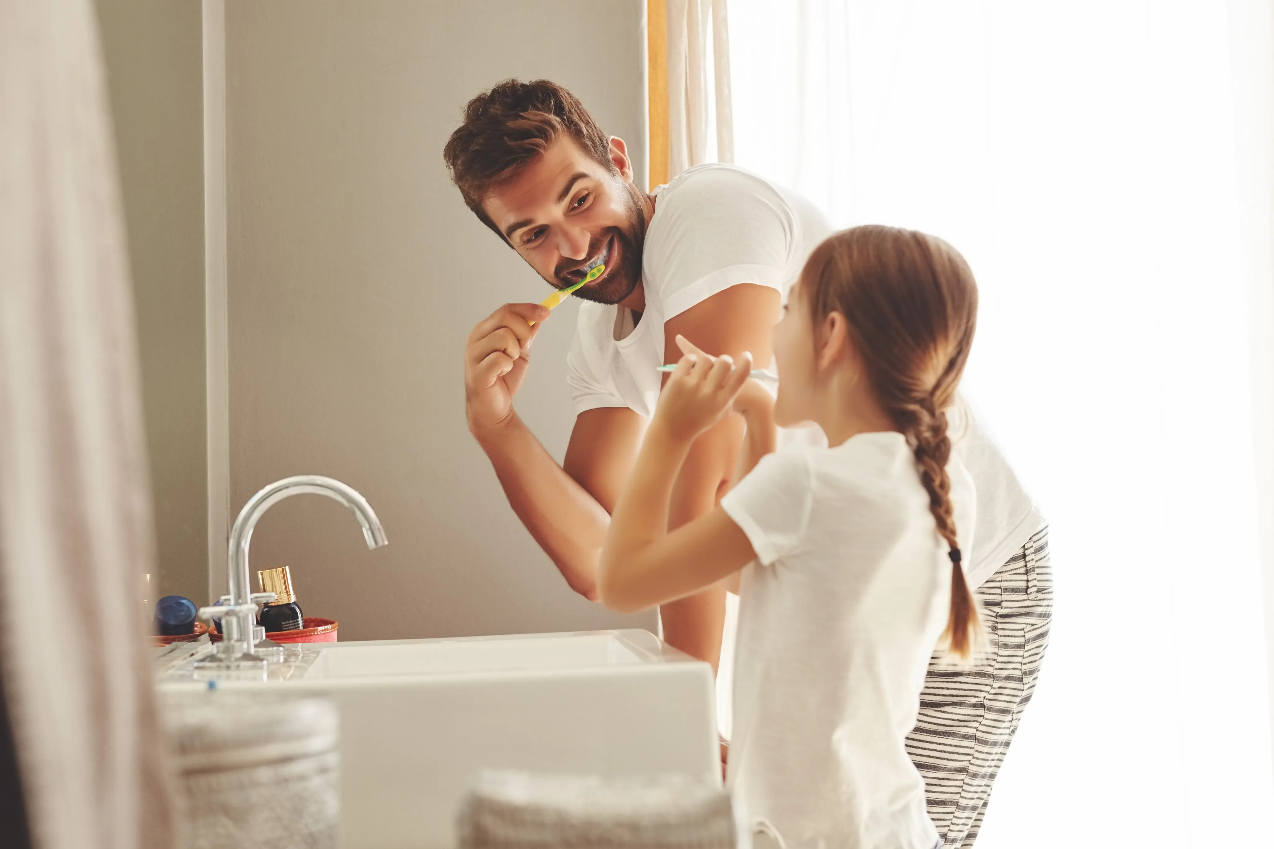 Father and daughter brushing teeth together